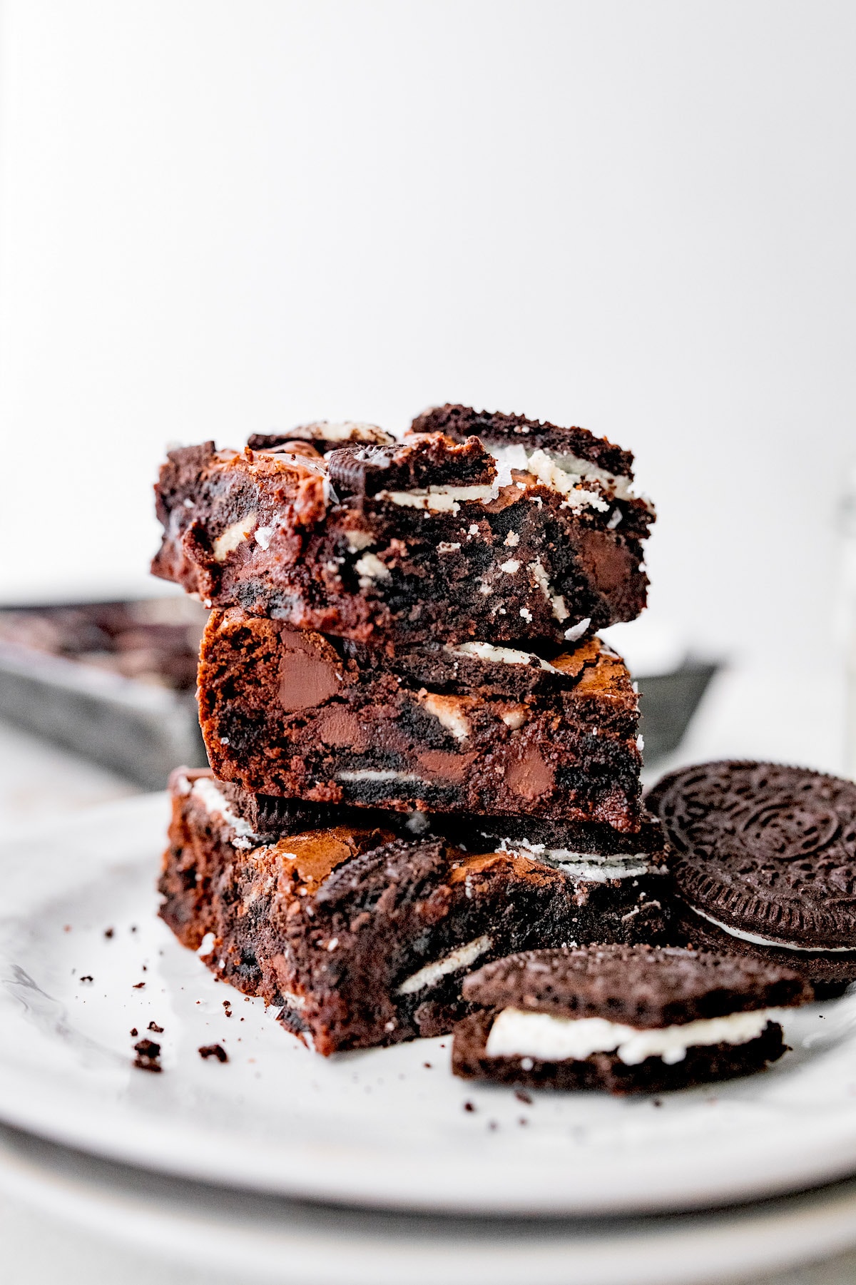 Oreo brownies stacked on plate with Oreos. 