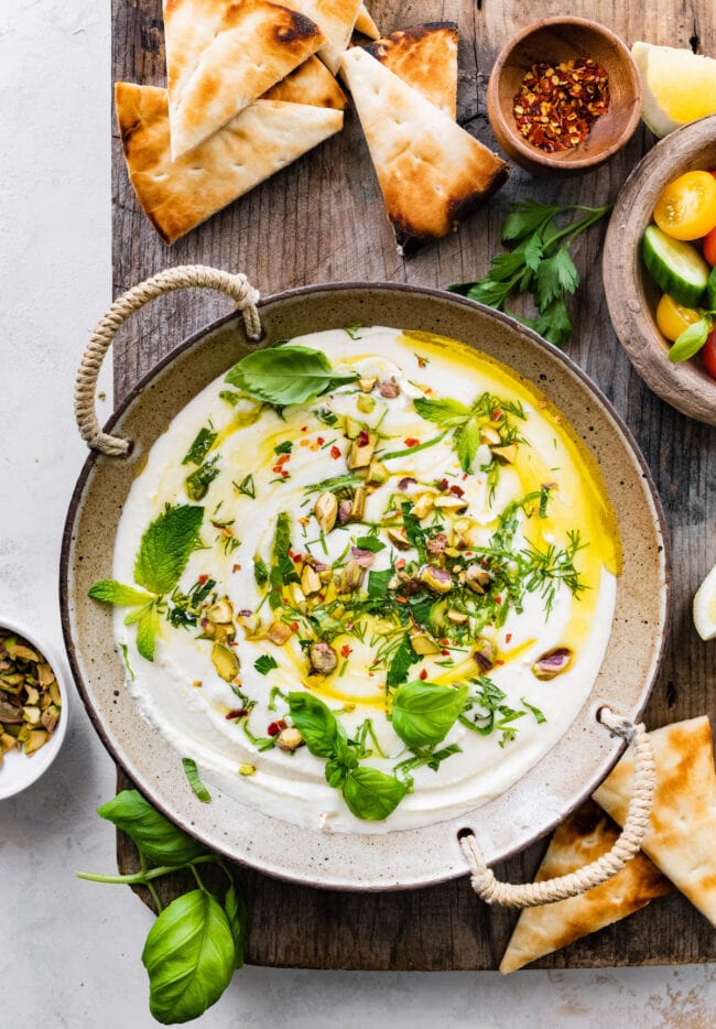 whipped feta dip in bowl with herbs.