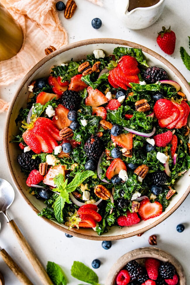 kale salad with berries in a bowl. 