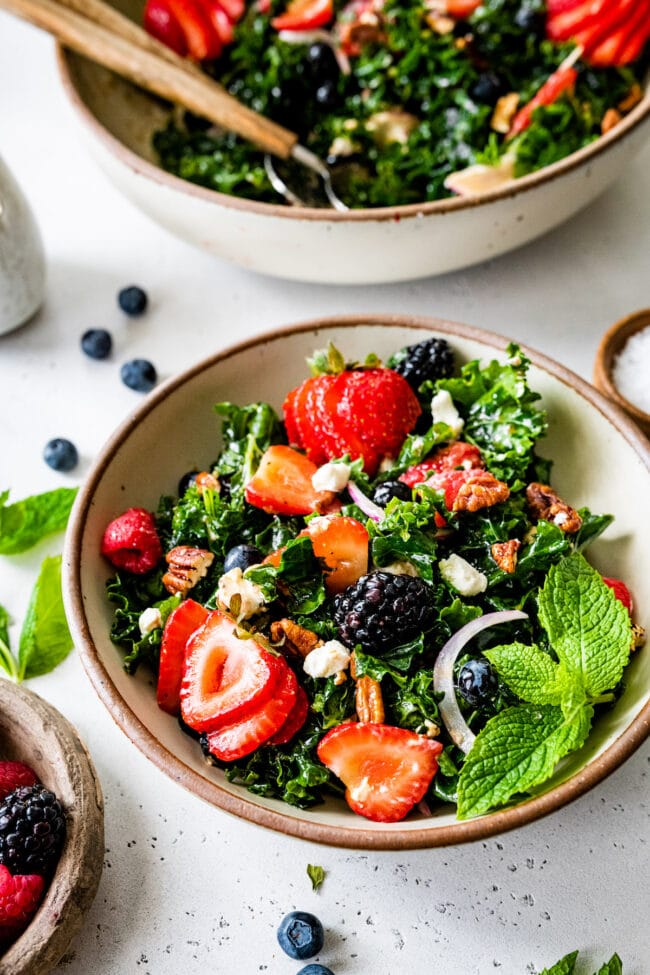 kale salad with berries and balsamic vinaigrette in bowl. 