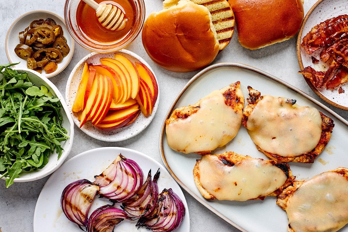 grilled chicken sandwich ingredients and grilled chicken with melty cheese on platter.