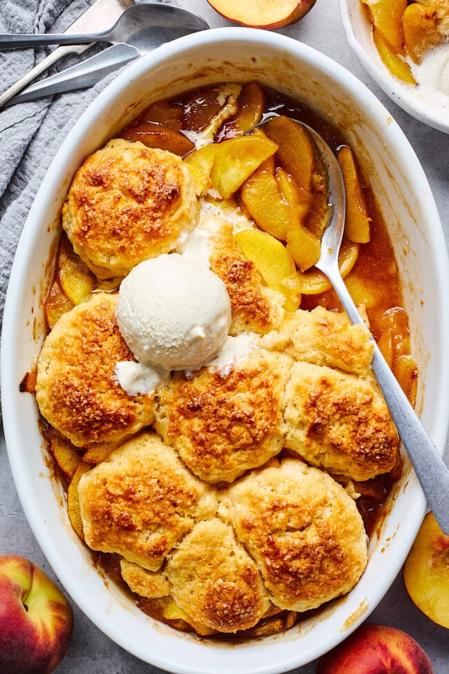 peach cobbler in  baking dish with vanilla ice cream.