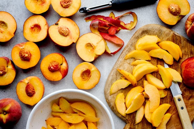 peaches and peach slices on cutting board. 