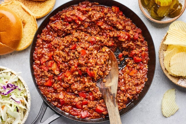 sloppy joe mixture in skillet with wood spoon.