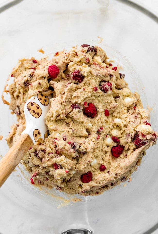 white chocolate raspberry cookie dough in bowl with spatula. 