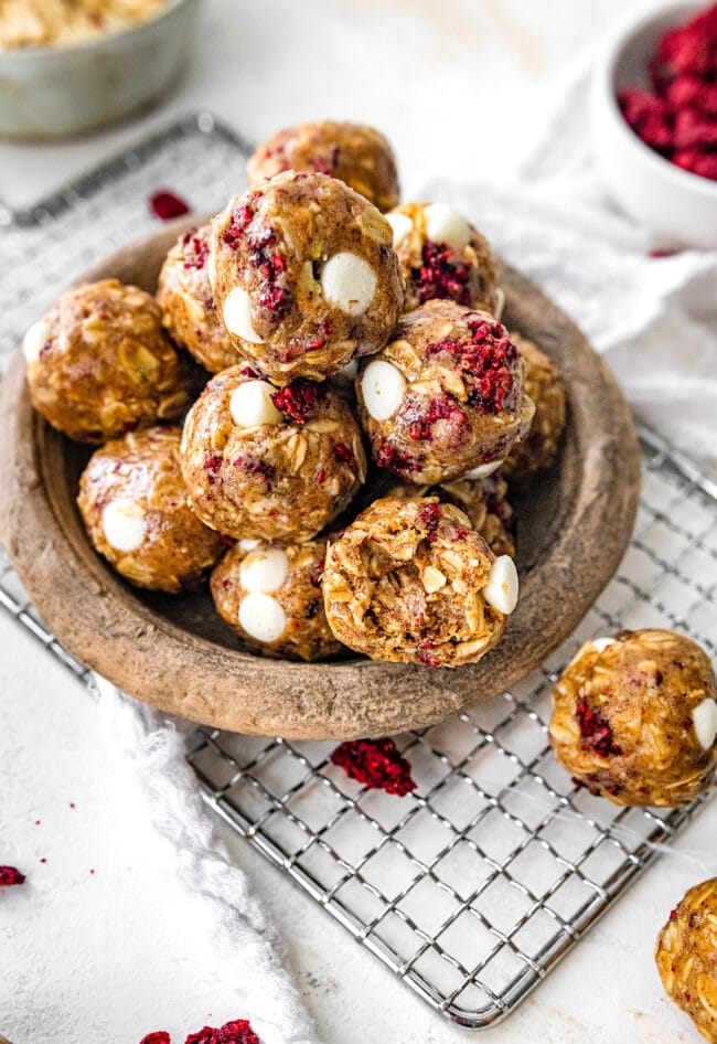 white chocolate raspberry energy balls in wood bowl.