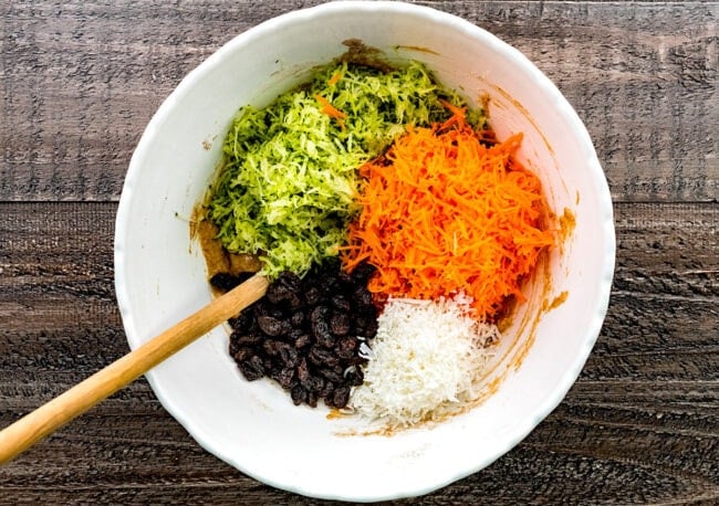 zucchini carrot muffin ingredients in bowl with spoon.