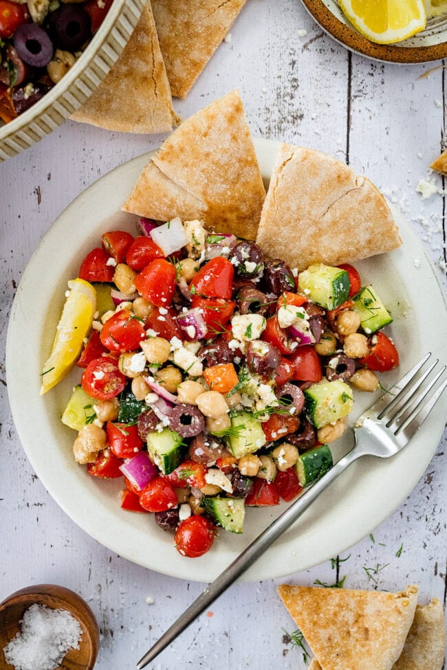 Greek chickpea salad on plate with fork and pita bread.