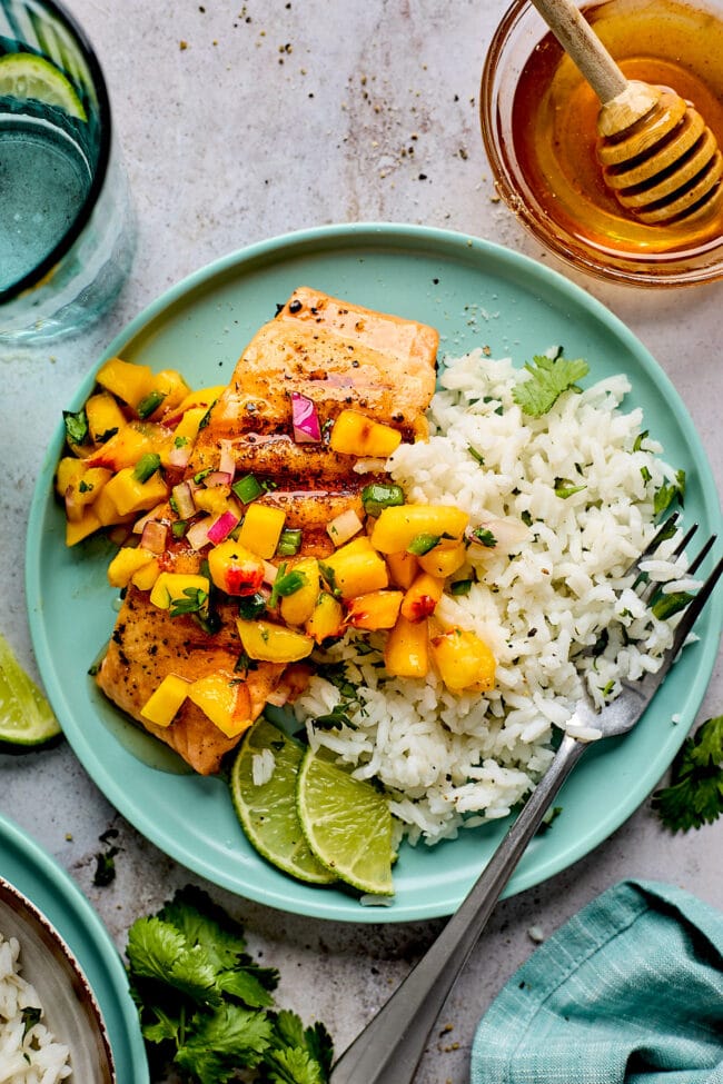 grilled salmon with fresh mango peach salsa and rice on plate with fork.