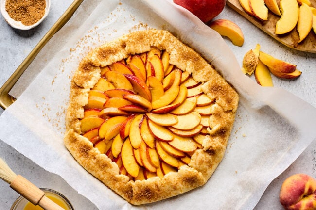 unbaked peach galette on baking sheet with parchment paper.