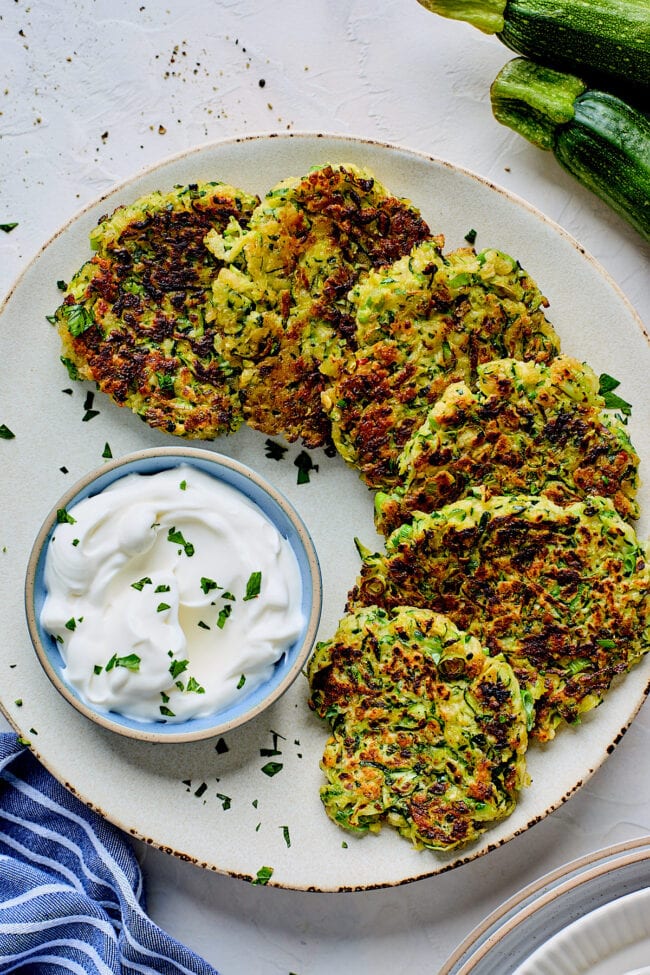 zucchini fritters on plate with sour cream.
