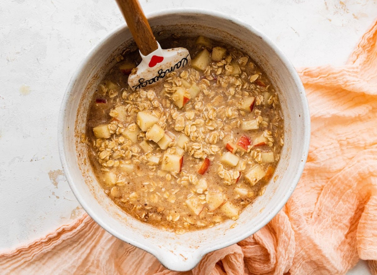 apple cinnamon baked oatmeal mixture in bowl with spatula.