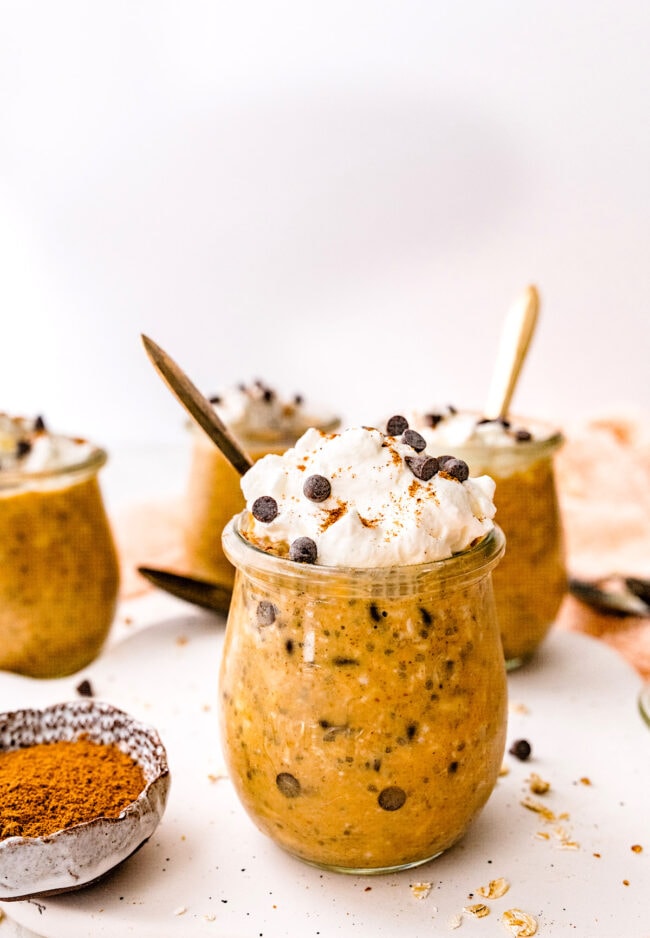 pumpkin overnight oats in jars with whipped cream and chocolate chips.