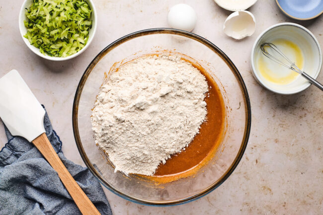 pumpkin zucchini bread ingredients in bowls with spatula. 