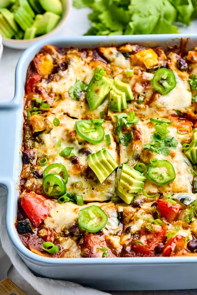 stacked vegetable enchiladas in pan cut in squares. 