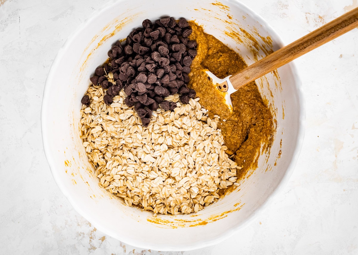 pumpkin breakfast cookie batter in bowl with oats and chocolate chips.
