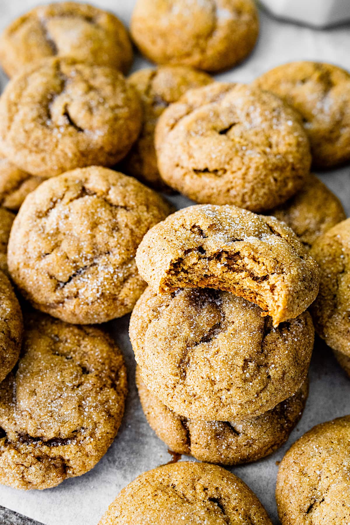 pumpkin gingersnap cookies topped with sugar and a bite out of one cookie.