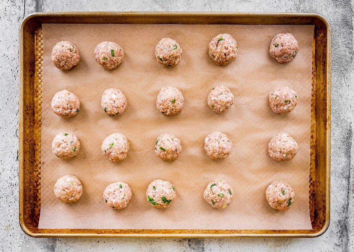 raw chicken teriyaki meatballs on baking sheet with parchment paper.