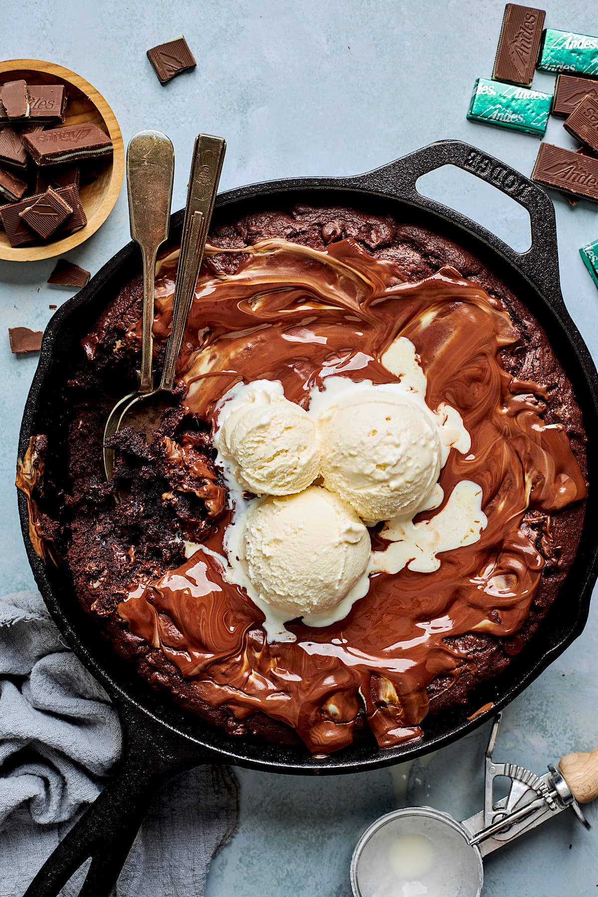 Andes mint skillet cookie in cast iron skillet with ice cream and two spoons.