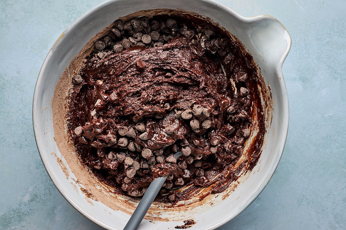 Andes mint cookie dough with chocolate chips in mixing bowl with spatula. 