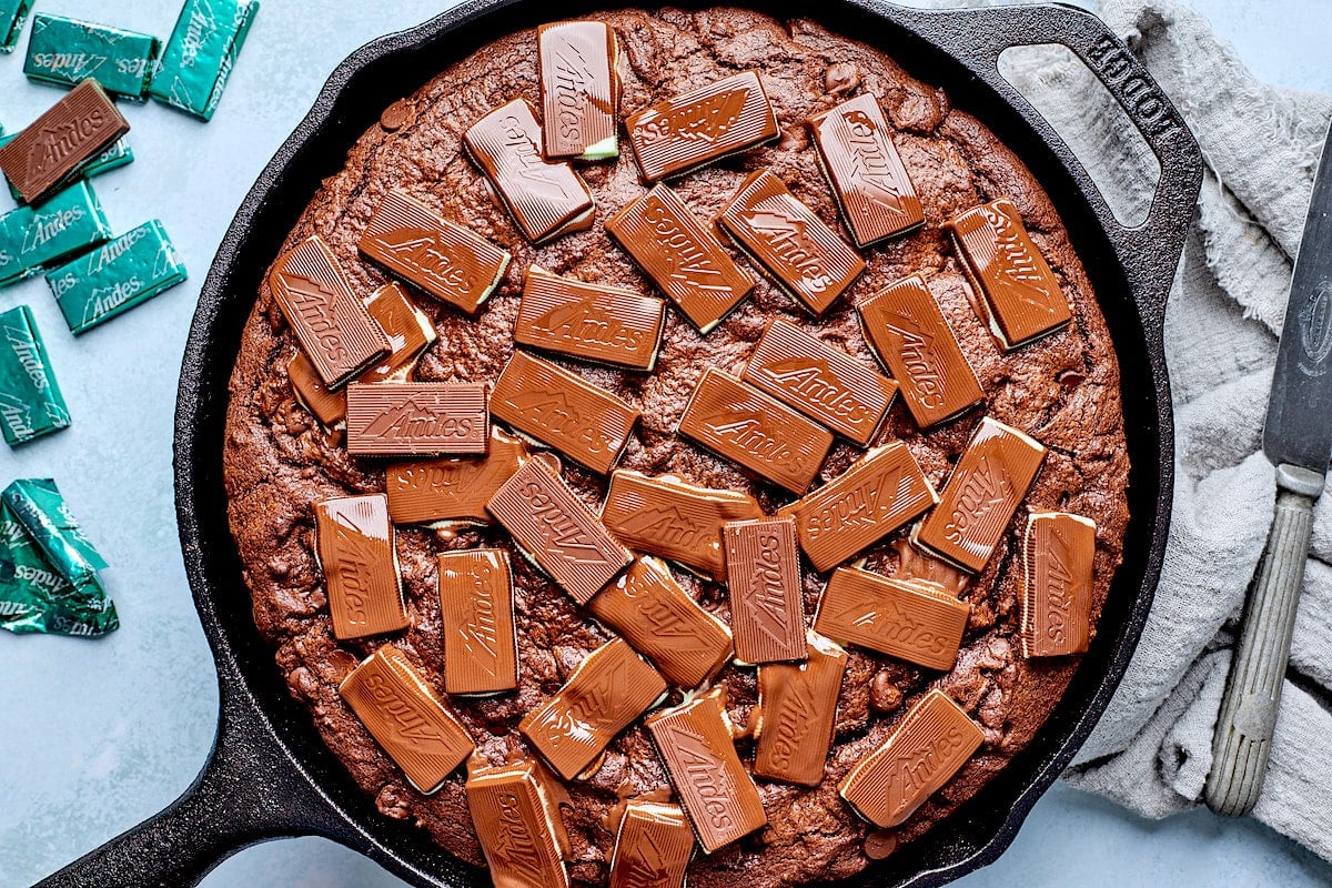 Andes mint skillet cookie in cast iron skillet with Andes mints melting on the top.