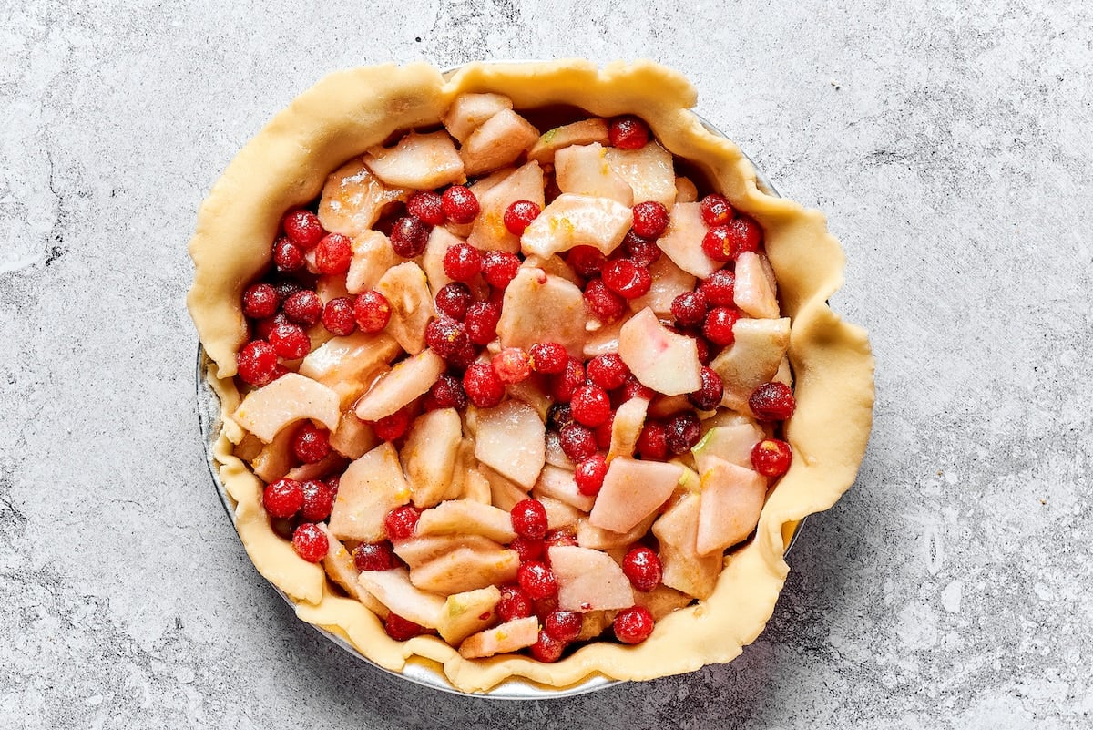 pie dough in pie pan with apple cranberry filling. 