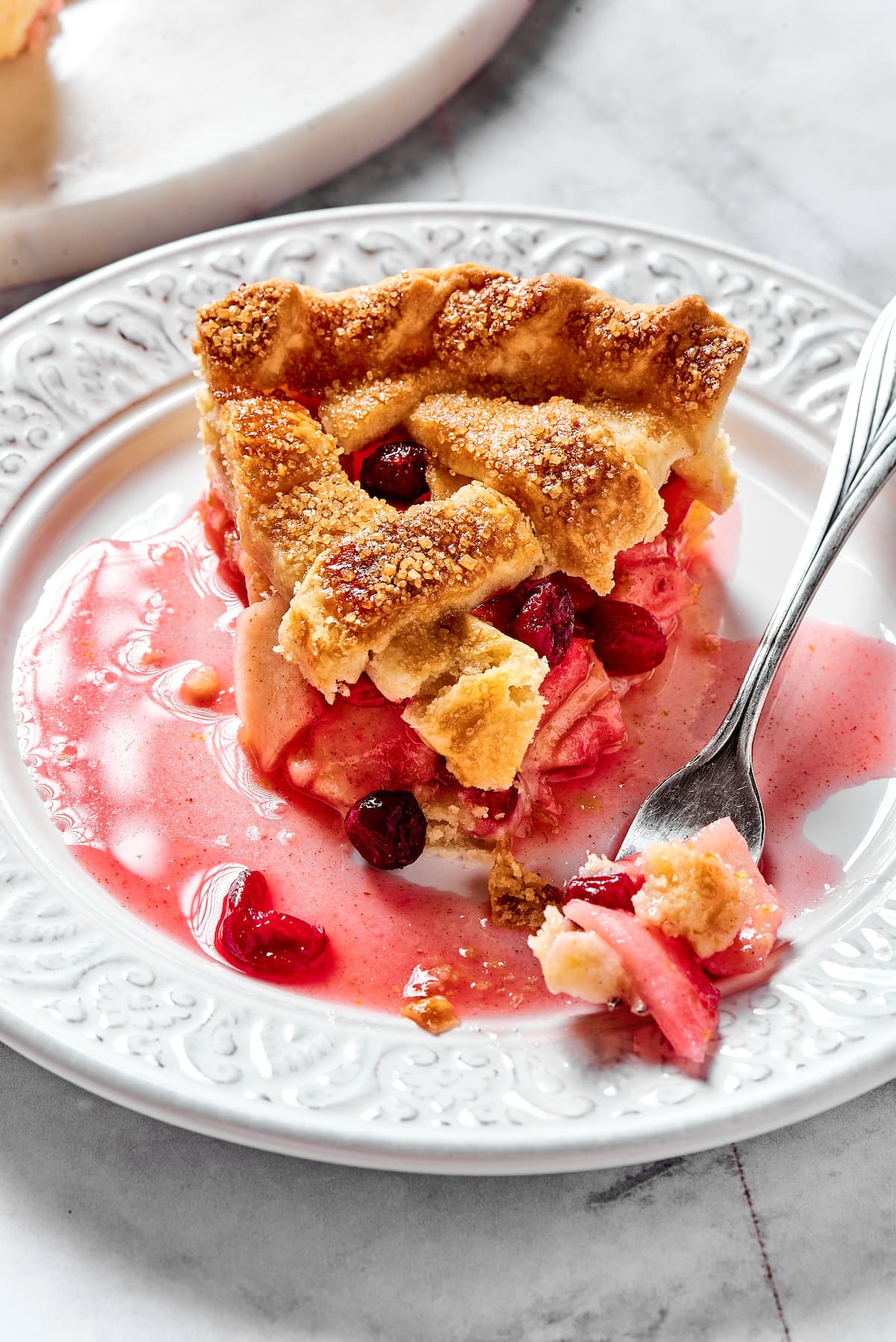 piece or apple cranberry pie on plate with fork. 