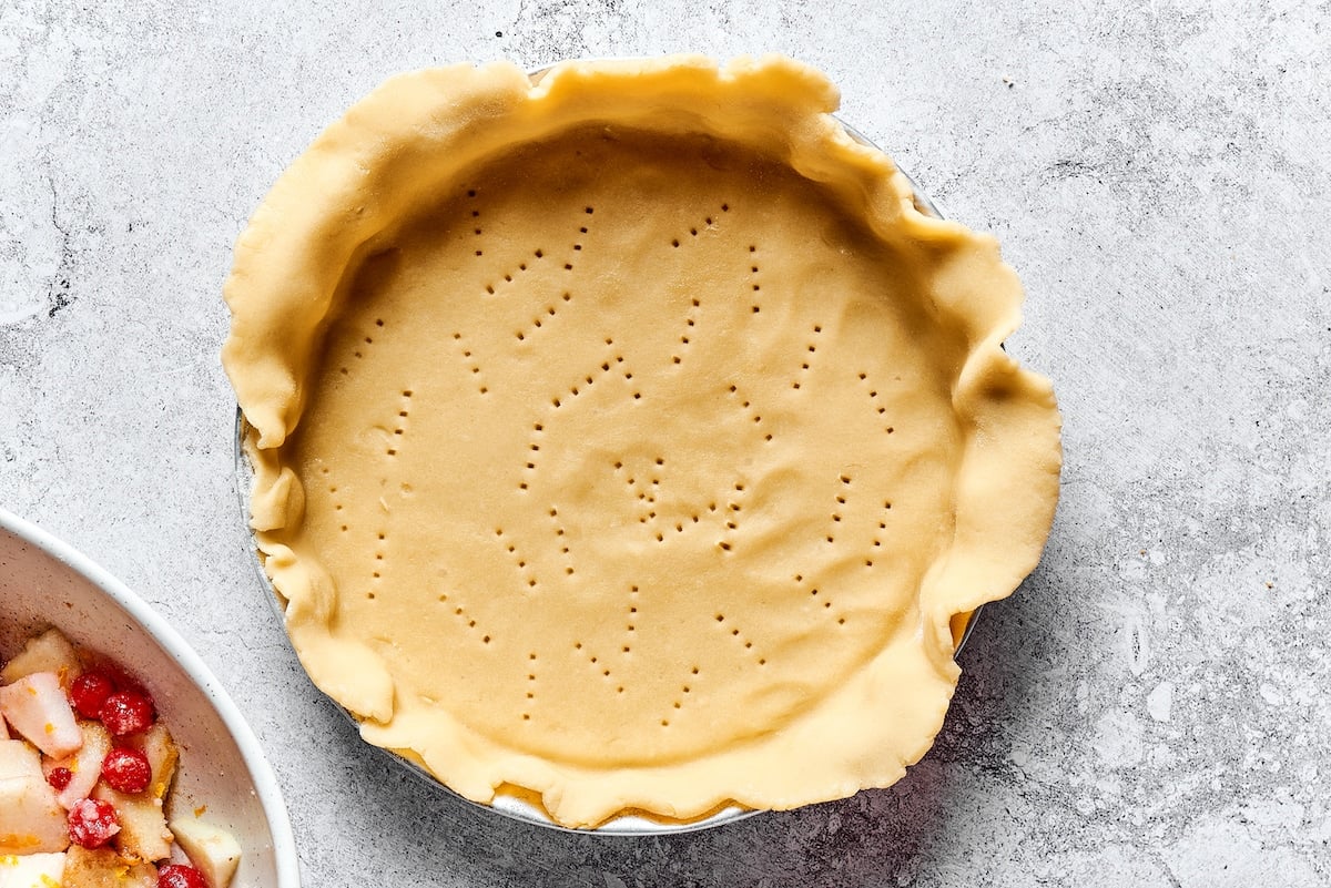 pie dough rolled out in pie pan with fork marks on the bottom. 