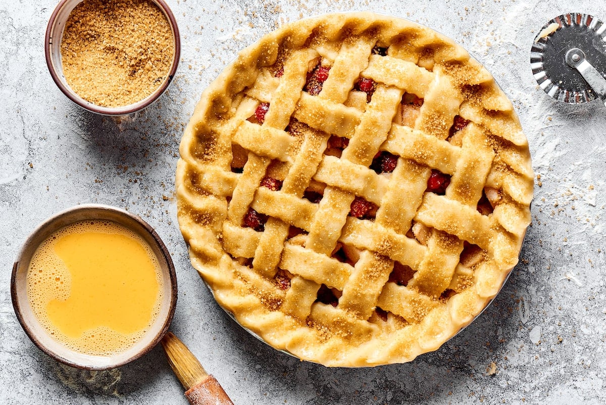 unbaked apple cranberry pie with lattice top brushed with egg wash and sprinkled with turbinado sugar.