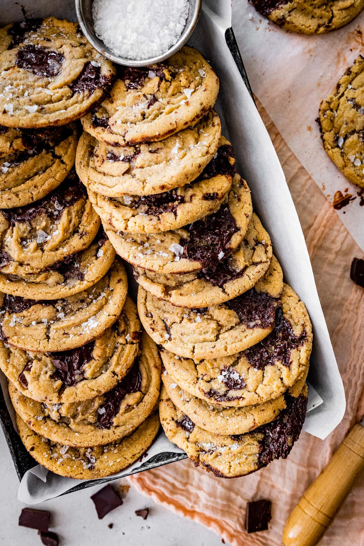 brown butter chocolate chip cookies with flaky sea salt in pan lined with parchment paper. 