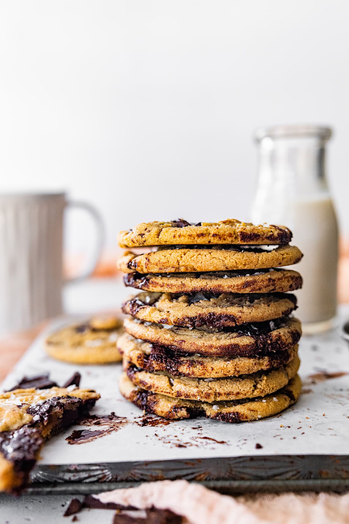 stack of brown butter chocolate chip cookies with bottle of milk and mug.