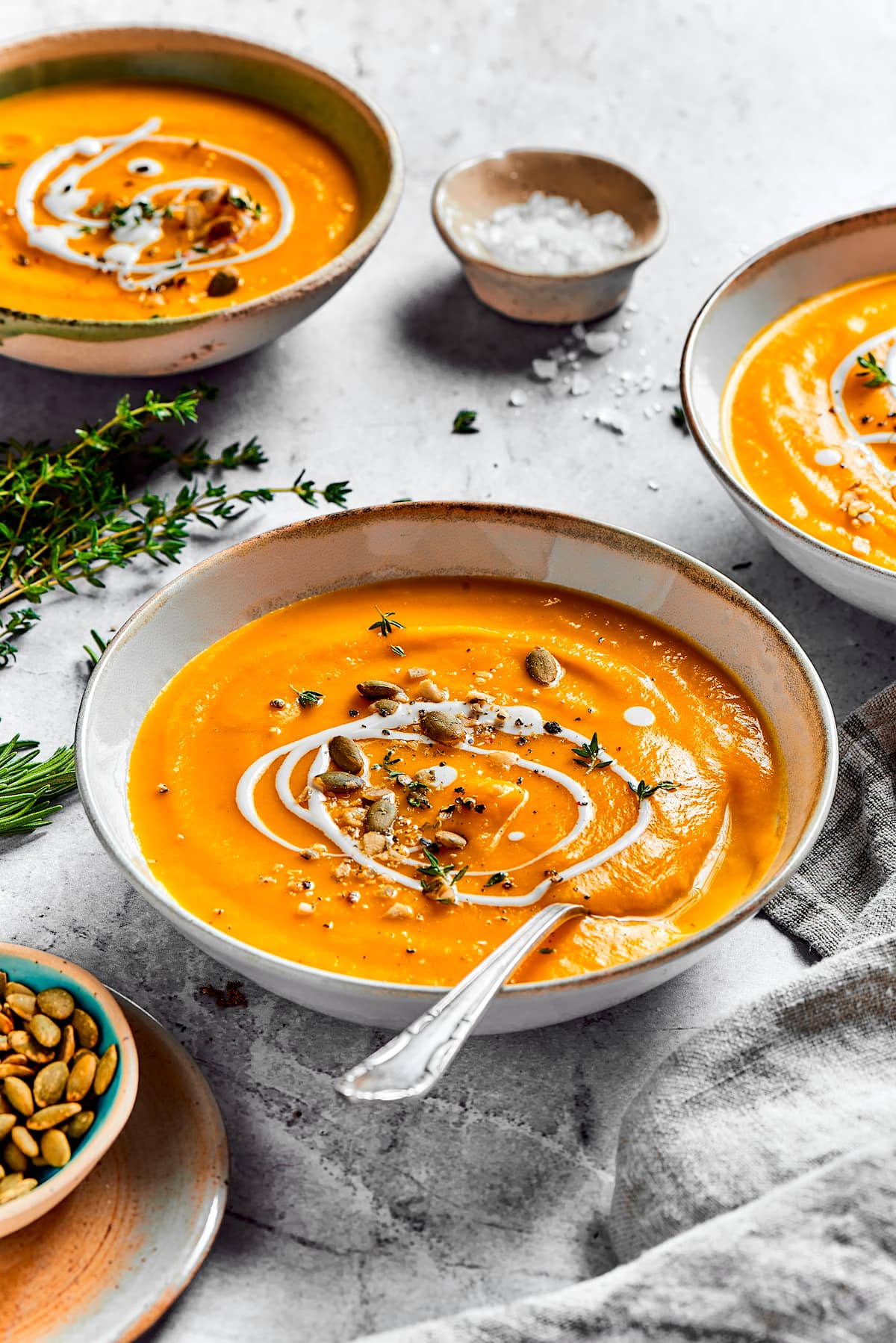 butternut squash soup in bowl with a spoon and drizzle of heavy cream. 