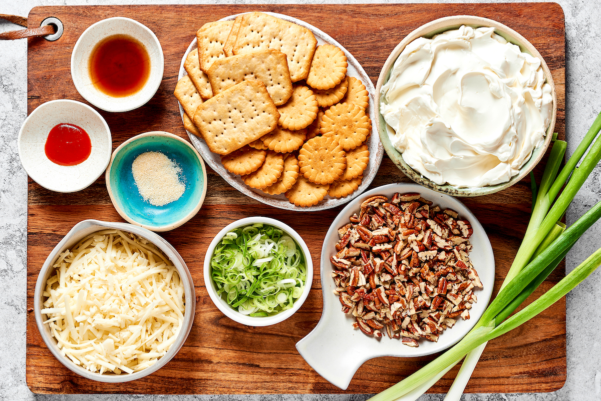 cheese ball ingredients in bowls on wood cutting board. 