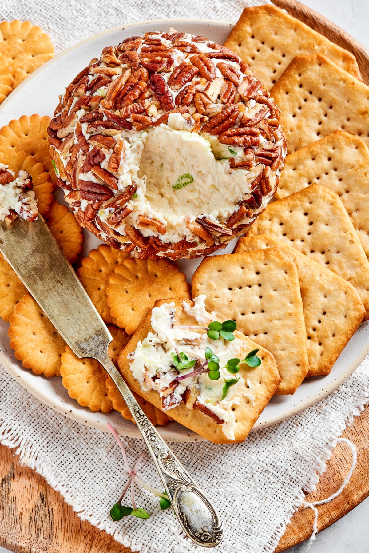 cheese ball on plate with crackers and cheese knife spreader. 