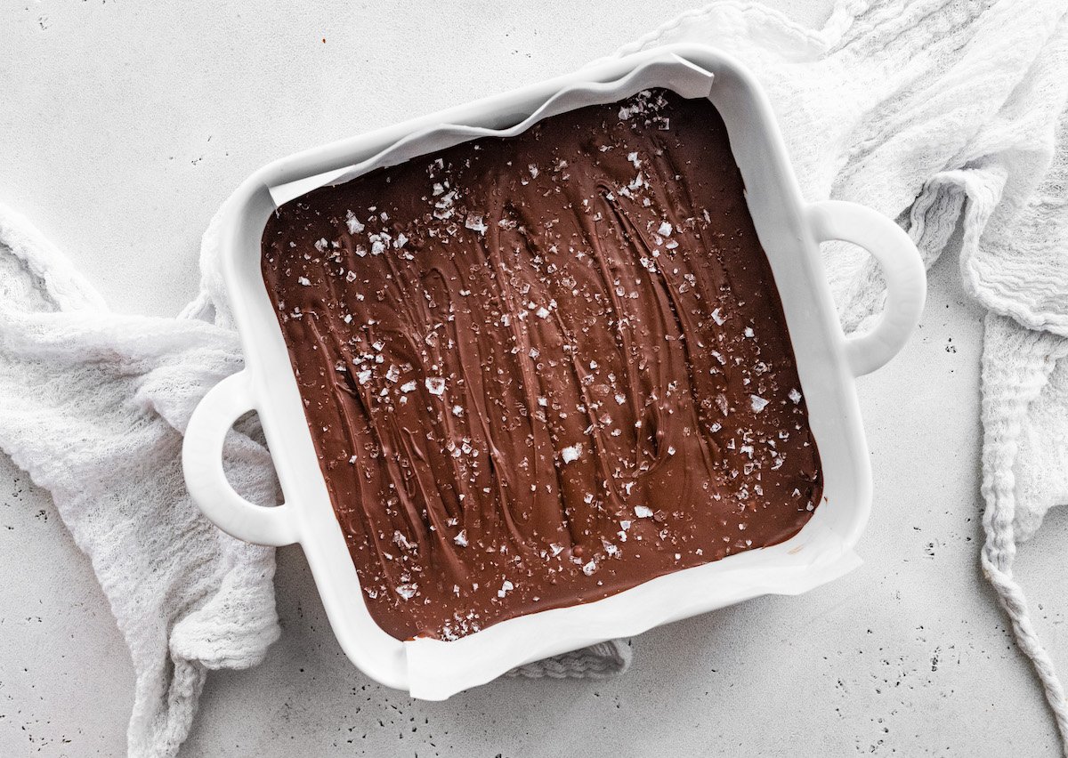 no bake peanut butter bars with chocolate and flaky sea salt in white baking dish.