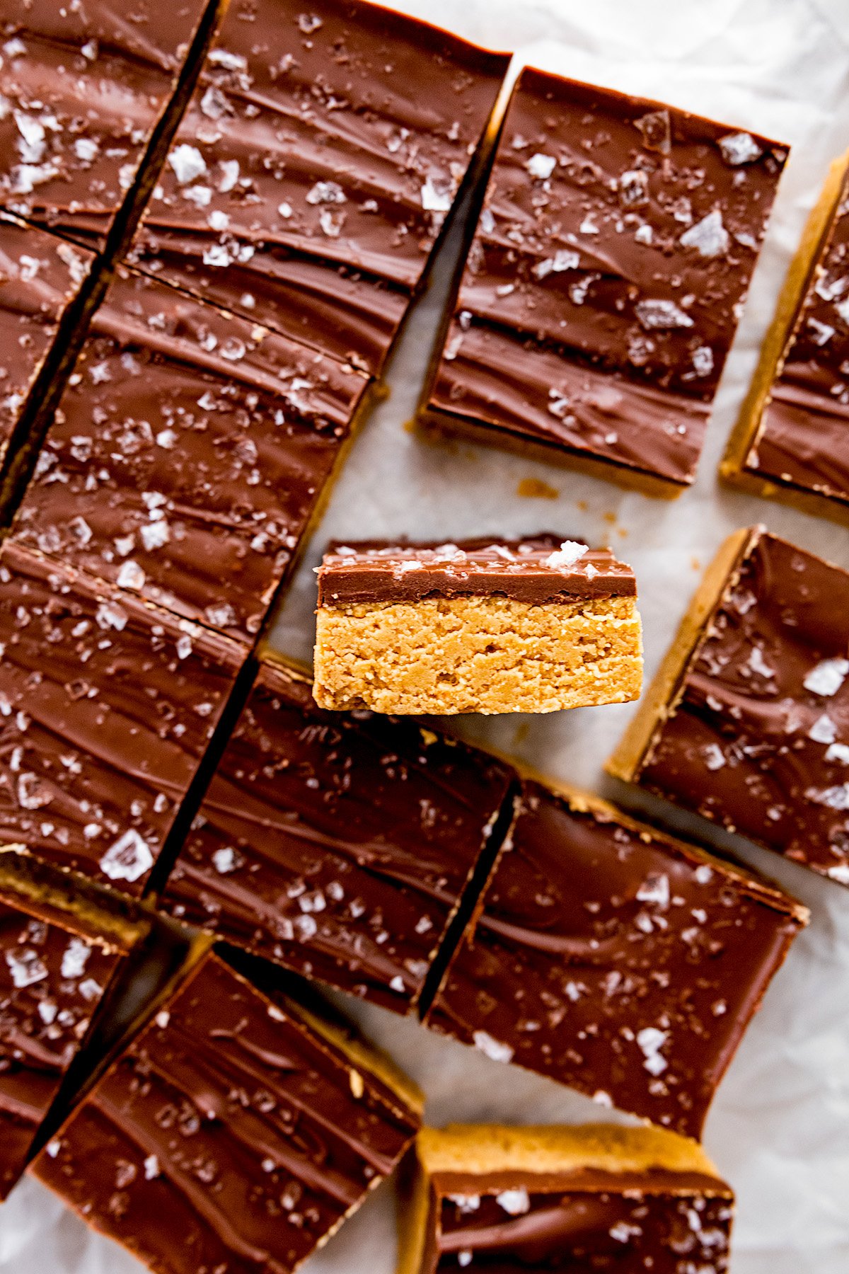 no bake peanut butter bars cut in squares with chocolate topping and flaky sea salt. 