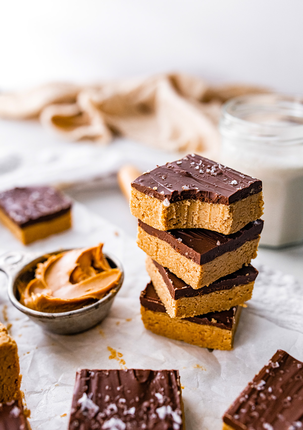 no bake peanut butter bars with chocolate top and flaky sea salt stacked.