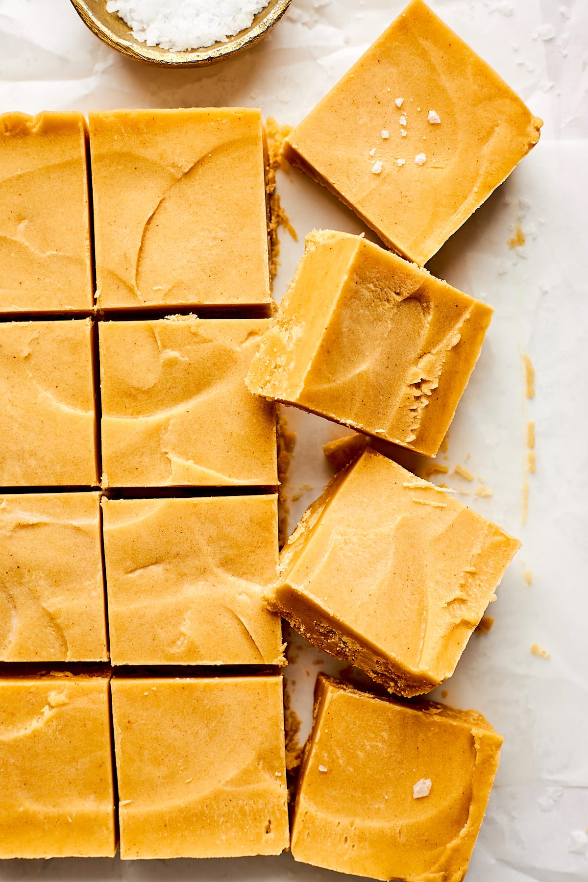 peanut butter fudge squares on parchment paper with flaky sea salt. 