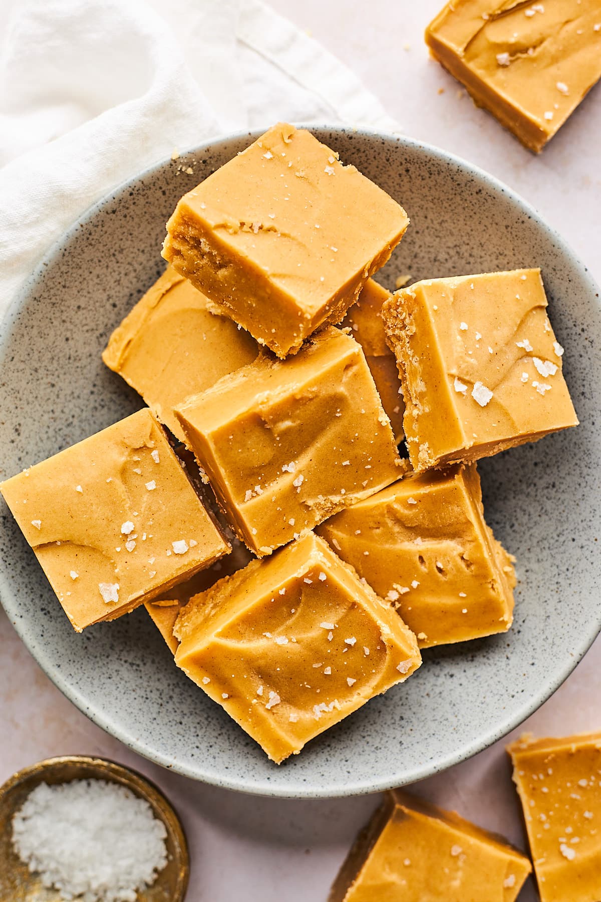 peanut butter fudge cut into squares on plate with flaky sea salt. 
