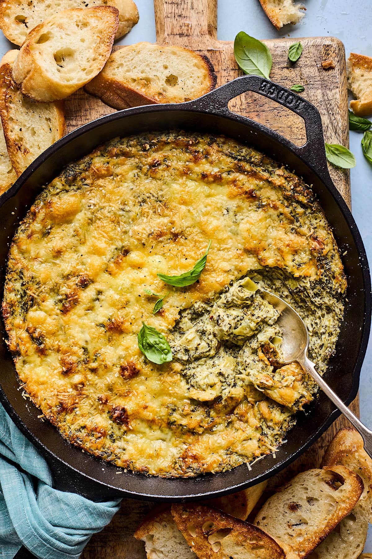 spinach artichoke dip in cast iron skillet with spoon. 