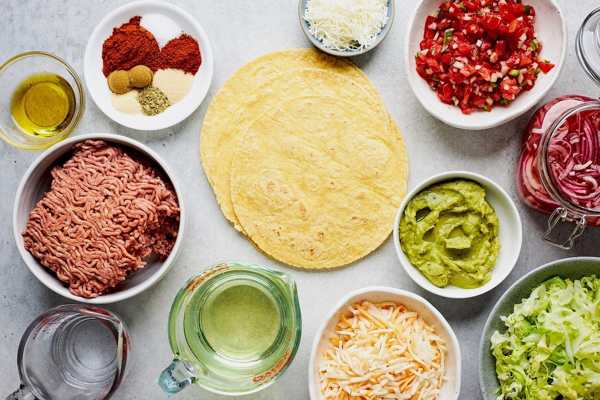 ground beef taco ingredients with tortillas and toppings. 
