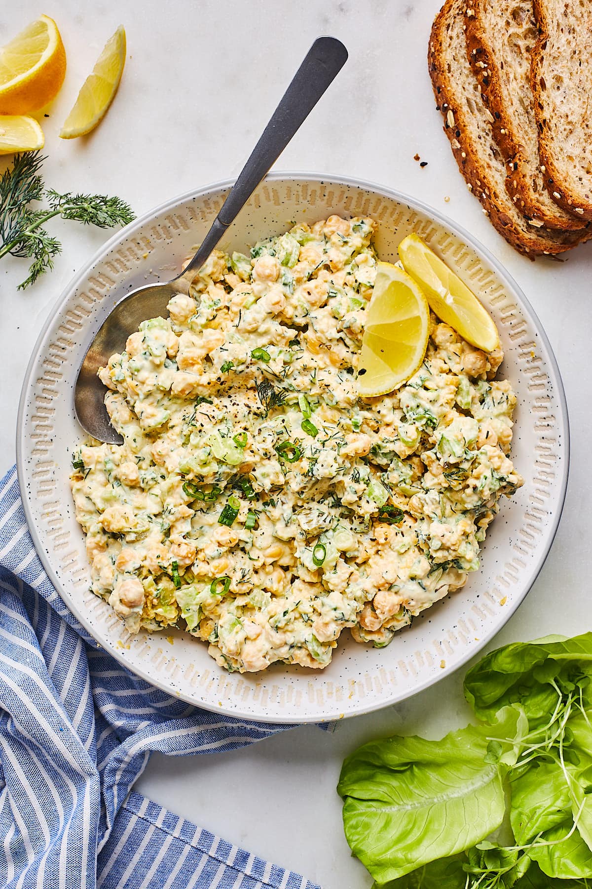 easy chickpea salad in bowl with spoon and lemon wedges. 