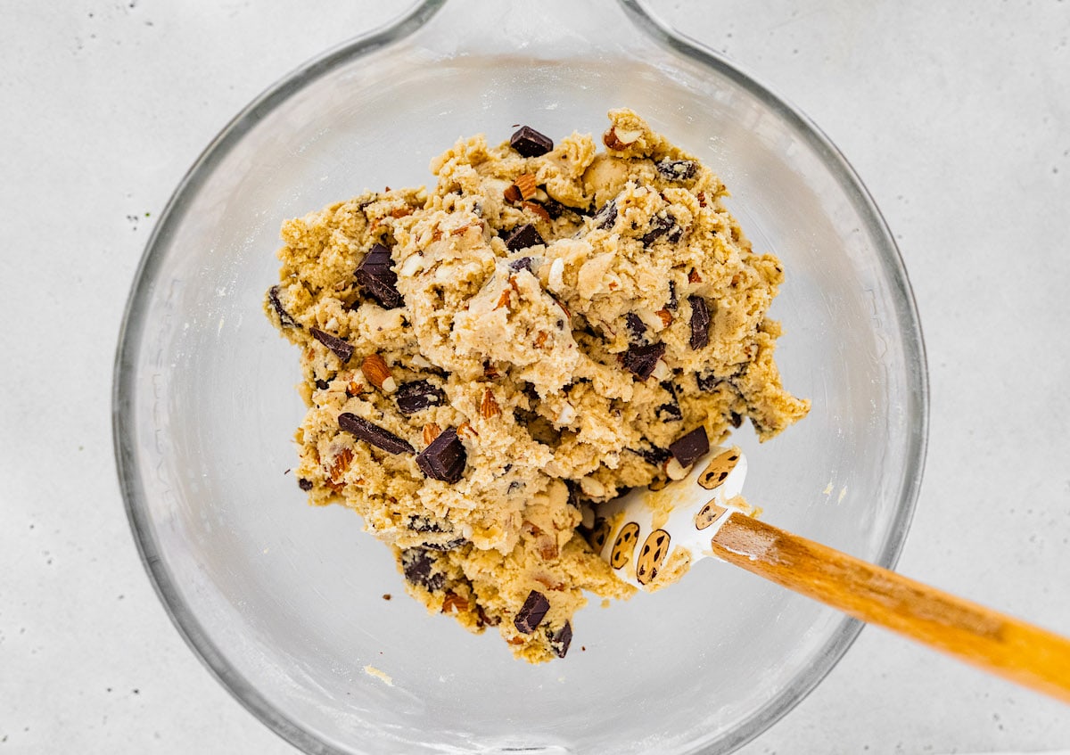 almond chocolate chip cookie dough in mixing bowl with spatula.