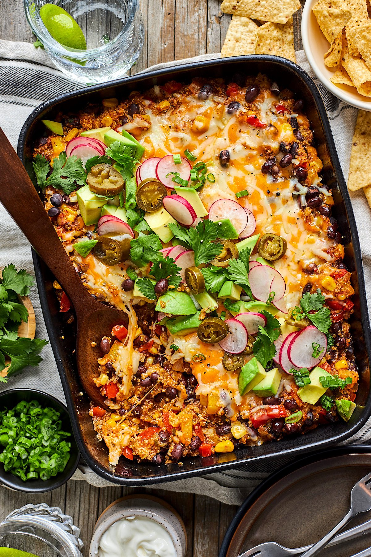 black bean quinoa enchilada bake in pan with wooden serving spoon.