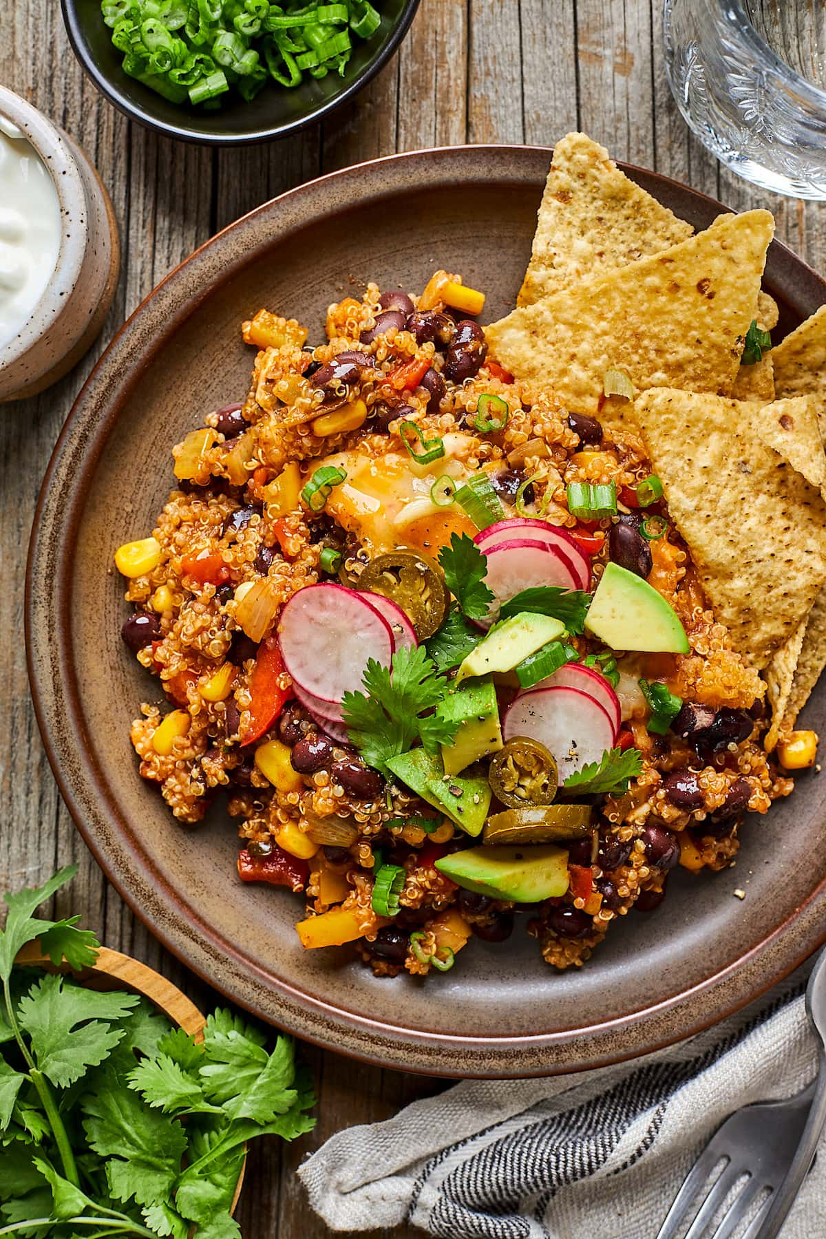 black bean quinoa enchilada bake on plate with toppings and tortilla chips.