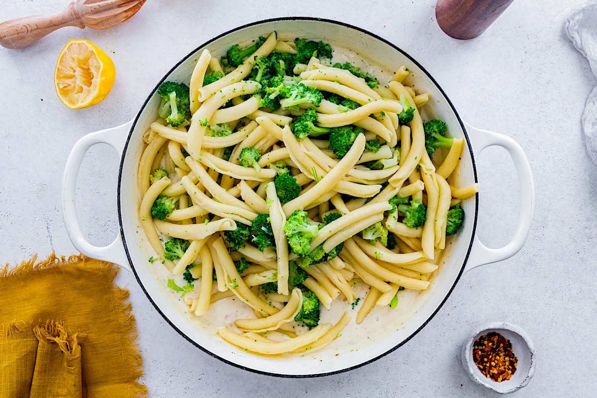 broccoli pasta in large white pot with cream sauce. 
