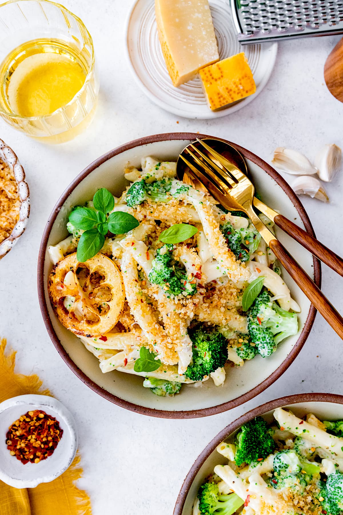 creamy broccoli pasta in bowl with toasted breadcrumbs, lemon slice, and silverware.