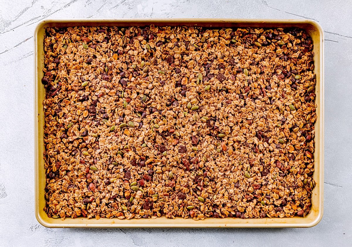 baked chocolate chip cookie granola cooling on large baking sheet. 