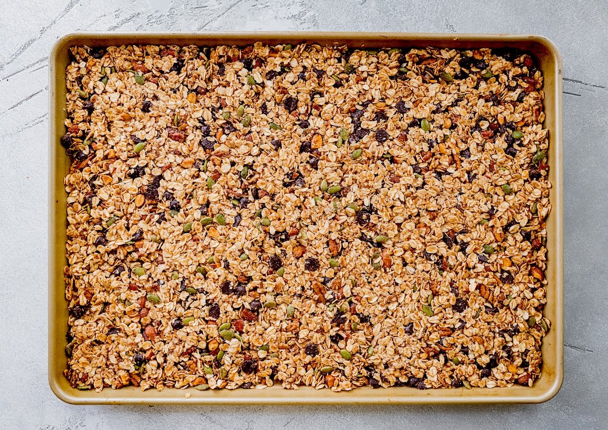 unbaked chocolate chip cookie granola pressed evenly onto a large baking sheet. 