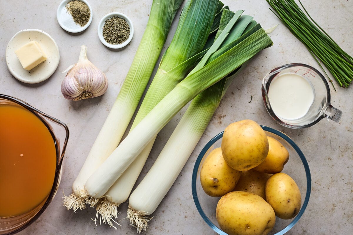 ingredients to make potato leek soup: leeks, potatoes, cream, broth, butter, garlic, and herbs.